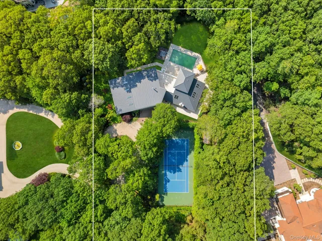 an aerial view of a house with a yard and trees all around