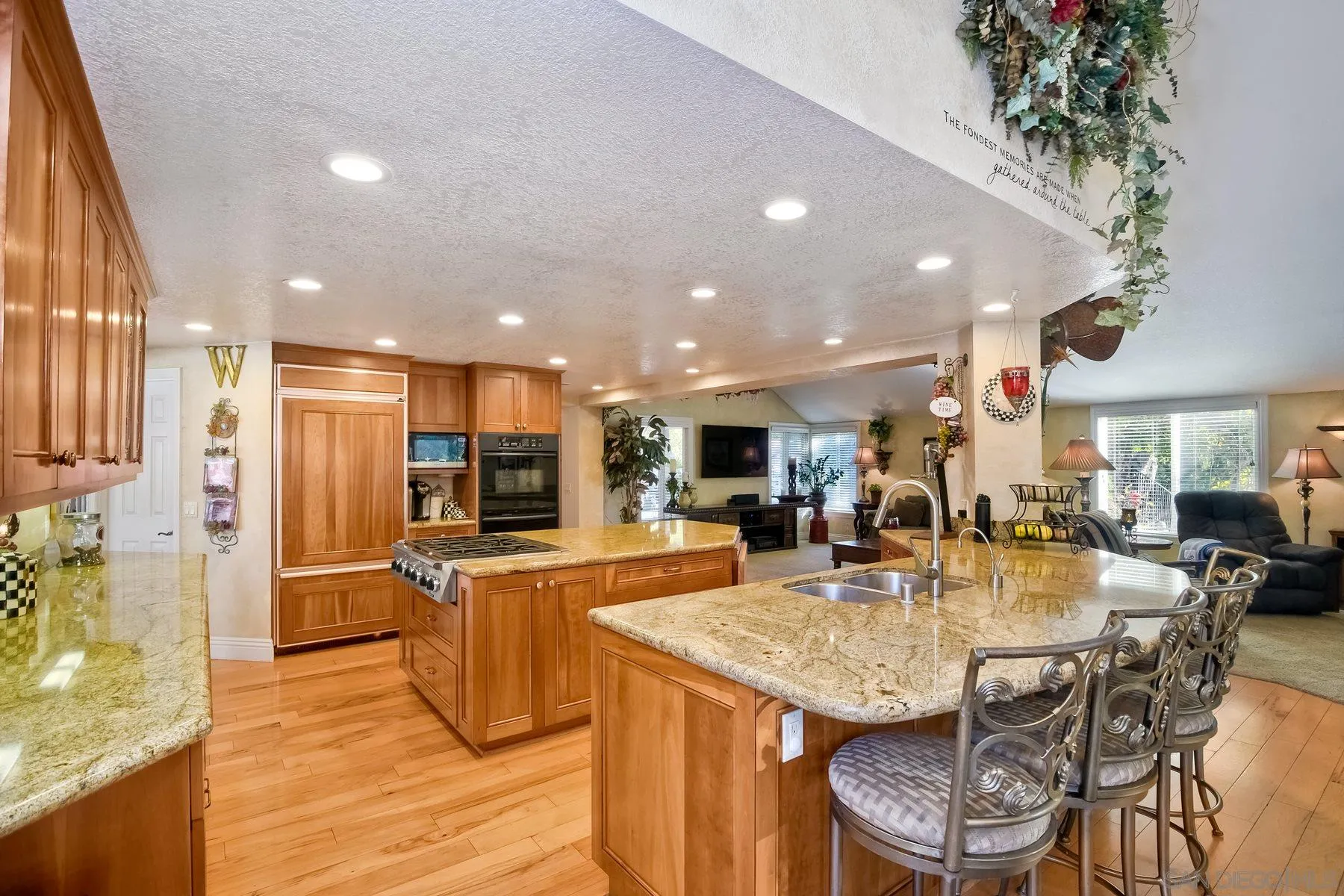 14248 Ipava Drive Poway, CA 92064 - Photo 12 of 34 a kitchen with stainless steel appliances kitchen island granite countertop a table chairs and a refrigerator