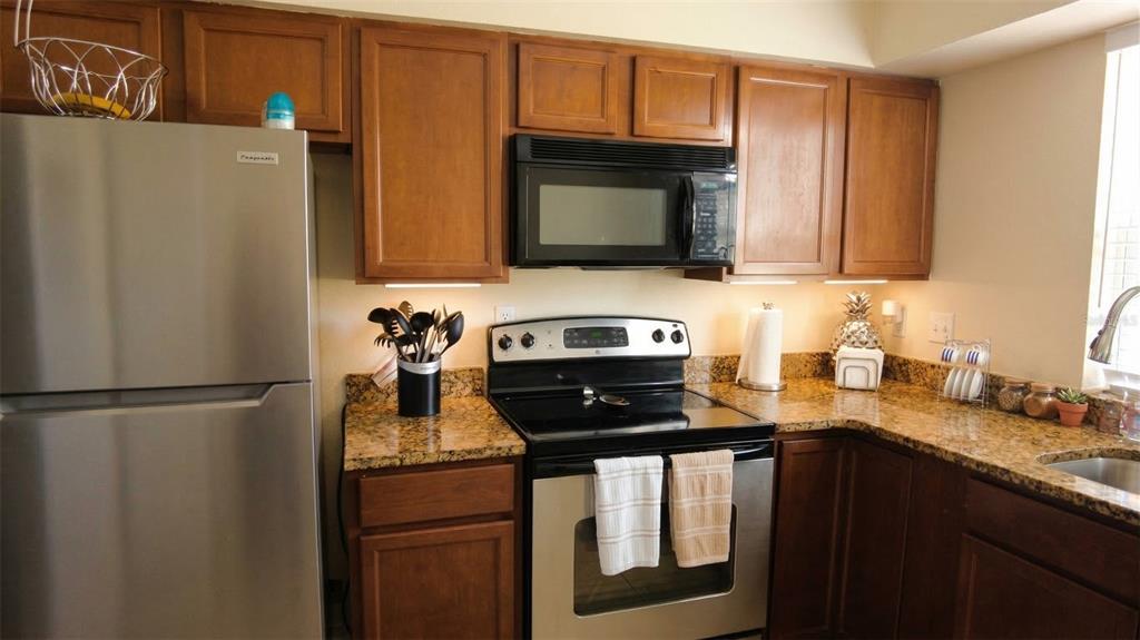 7327 Abonado Road, Unit 7327 Tampa, FL 33615 - Photo 3 of 9 a kitchen with granite countertop stainless steel appliances a refrigerator a stove a sink and a microwave