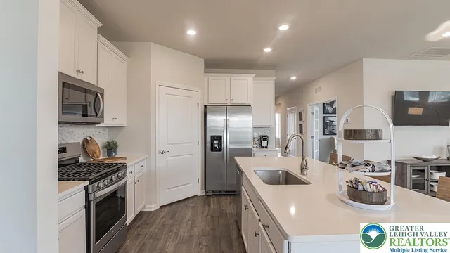 a kitchen with kitchen island a stove a sink a refrigerator and cabinets