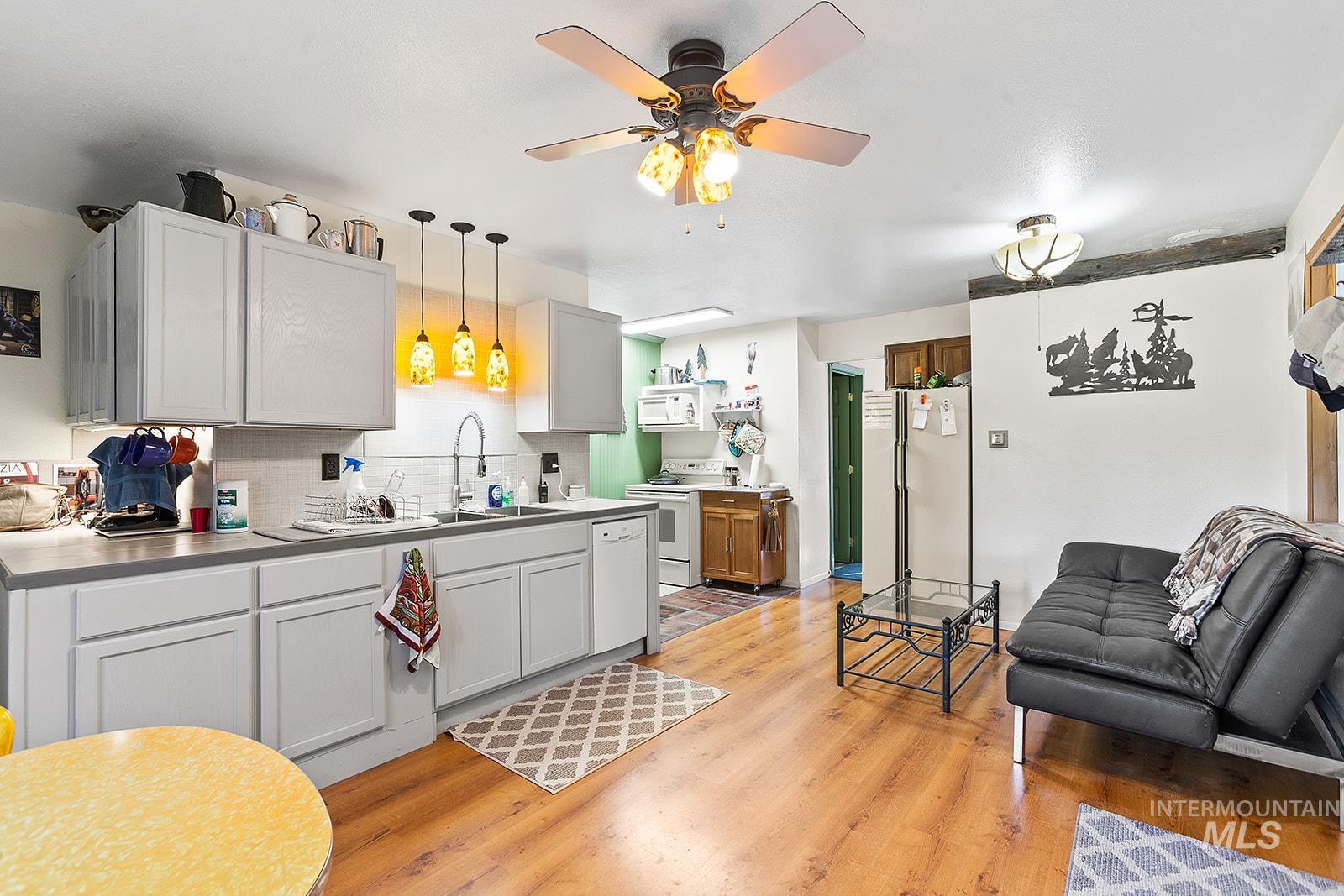 25314 Soldiers Meadow Road Winchester, ID 83555 - Photo 12 of 45 Kitchen featuring backsplash, white appliances, light wood-style floors, a ceiling fan, and hanging light fixtures