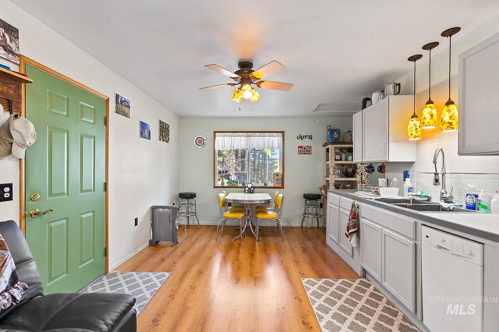 25314 Soldiers Meadow Road Winchester, ID 83555 - Photo 13 of 45 Kitchen with white dishwasher, light wood-style flooring, hanging light fixtures, decorative backsplash, and a ceiling fan