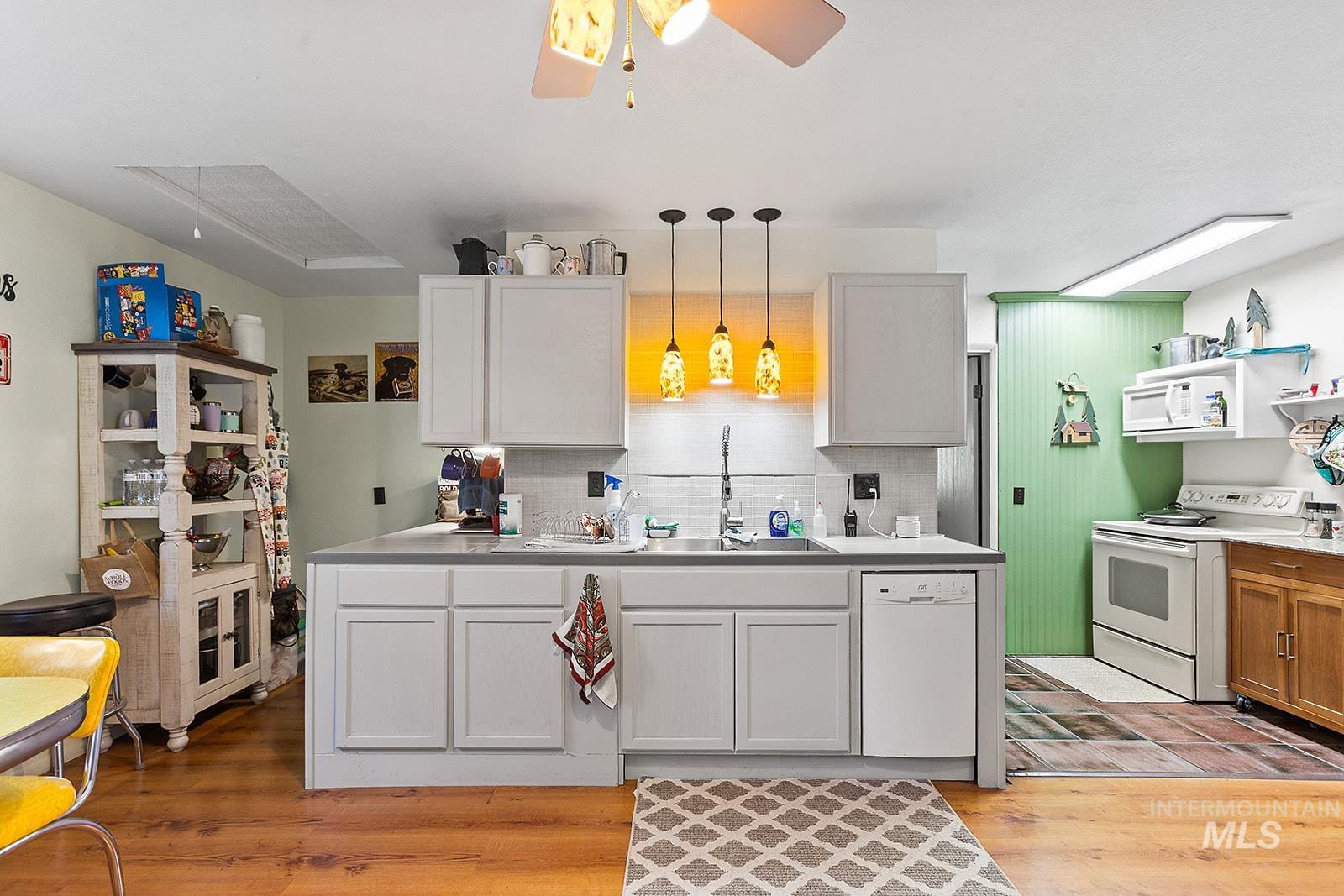 25314 Soldiers Meadow Road Winchester, ID 83555 - Photo 14 of 45 Kitchen featuring white appliances, tasteful backsplash, light countertops, and light wood-style floors