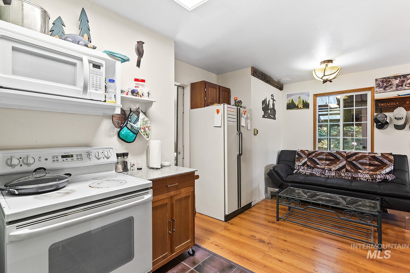 25314 Soldiers Meadow Road Winchester, ID 83555 - Photo 15 of 45 Kitchen featuring white appliances, brown cabinetry, and dark wood-type flooring