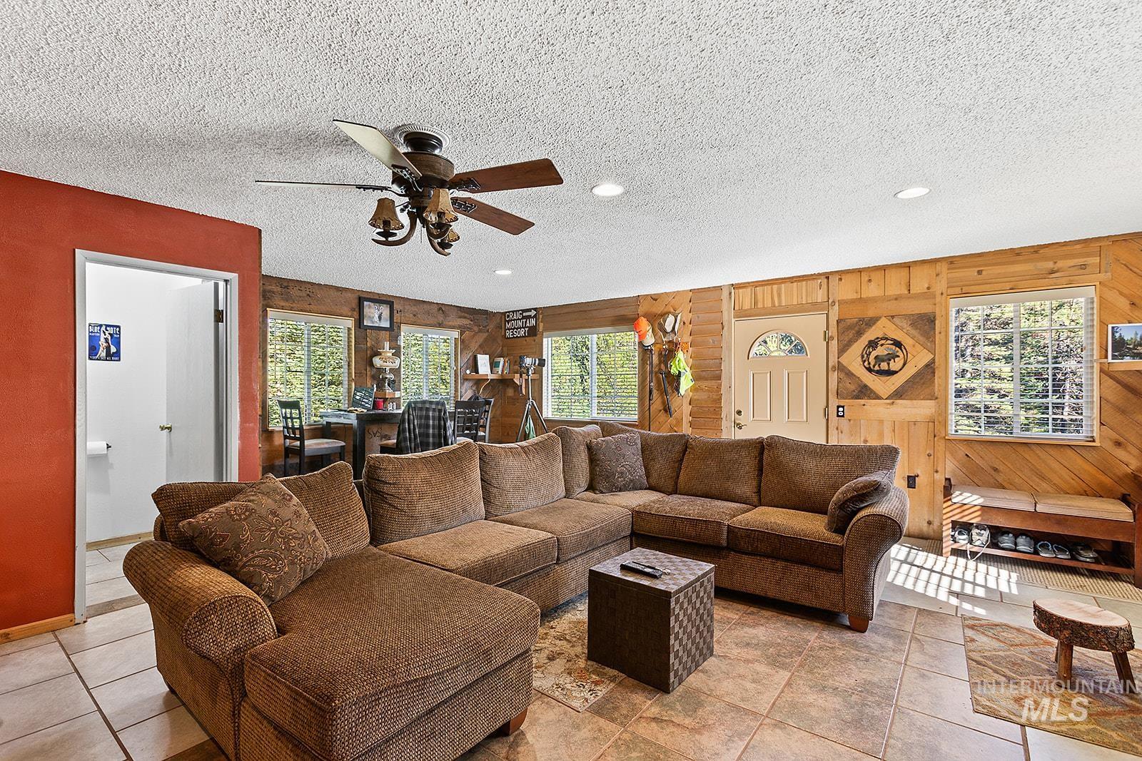 25314 Soldiers Meadow Road Winchester, ID 83555 - Photo 10 of 45 Tiled living area with a textured ceiling, healthy amount of natural light, ceiling fan, wood walls, and recessed lighting
