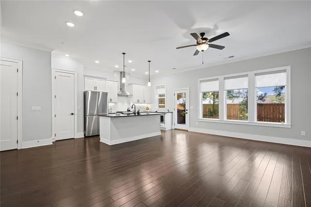 a view of an empty room with wooden floor and a ceiling fan