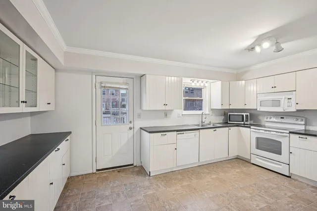 a kitchen with granite countertop white cabinets and white appliances