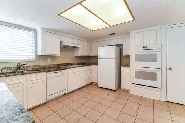 a kitchen with white cabinets and white appliances