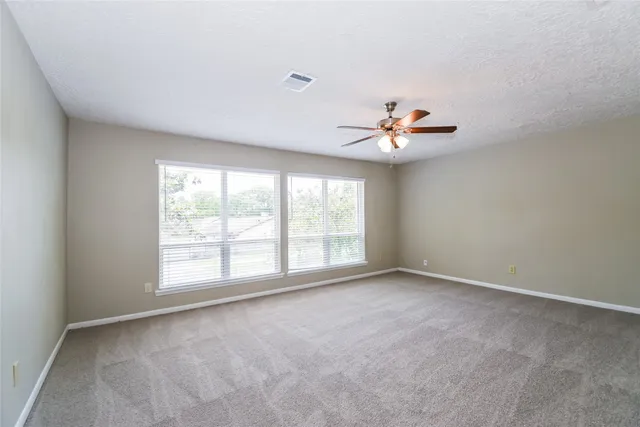 an empty room with a window and a ceiling fan