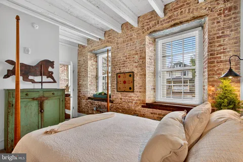 a bedroom with a bed dresser and a large window