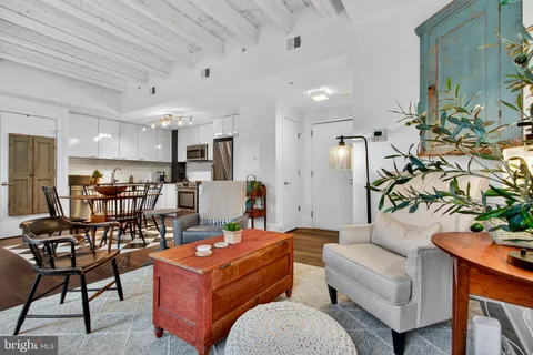 a living room with furniture and kitchen view with wooden floor