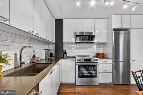 a kitchen with stainless steel appliances granite countertop a refrigerator a stove a sink and white cabinets