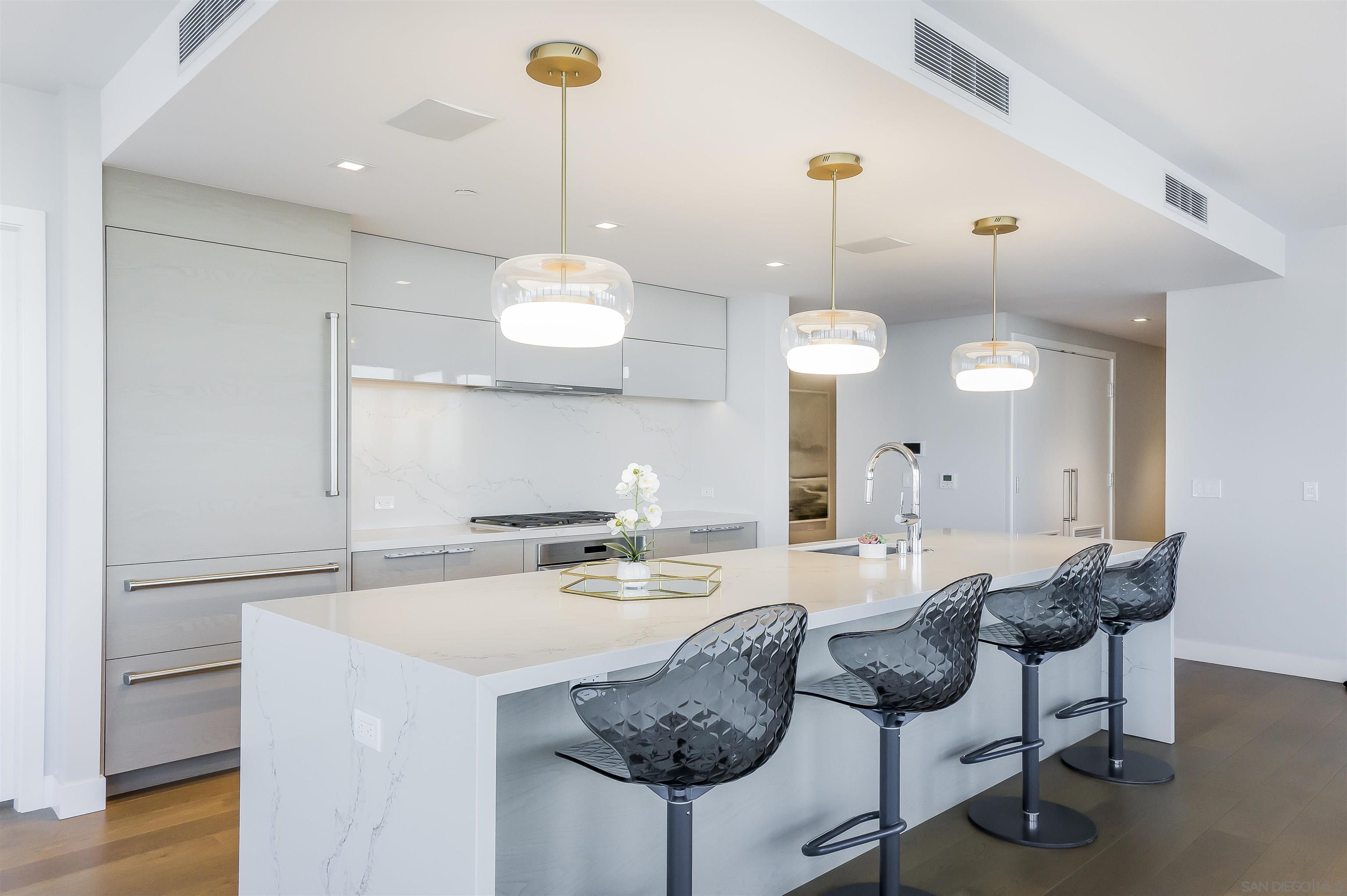 888 E Street, Unit 3602 San Diego, CA 92101 - Photo 12 of 51 a kitchen with a dining table chairs sink and cabinets