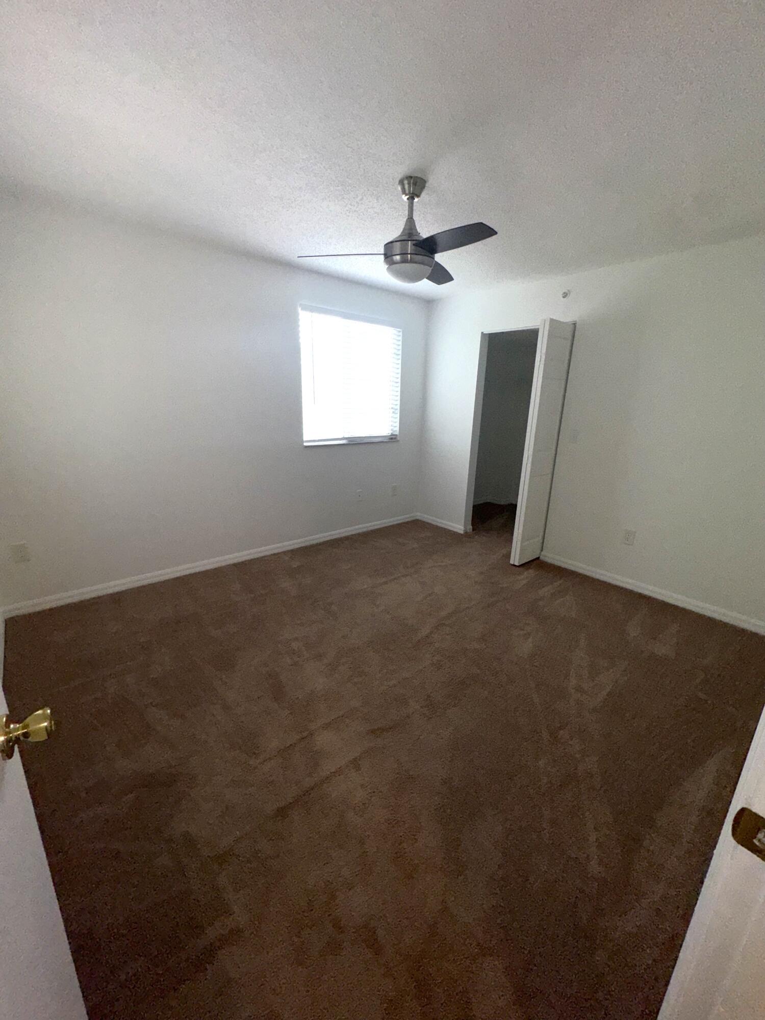 1300 Crestwood Court South, Unit 1319 Royal Palm Beach, FL 33411 - Photo 13 of 14 an empty room with windows and fan