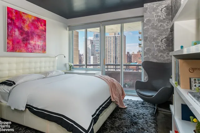 a bedroom with a bed chair and a large window