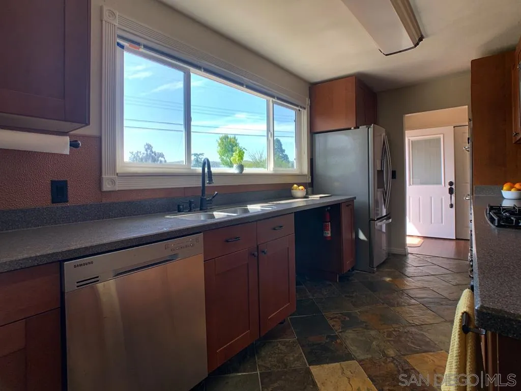 14416 Springvale Street Poway, CA 92064 - Photo 3 of 18 a kitchen with stainless steel appliances granite countertop a sink and a large window