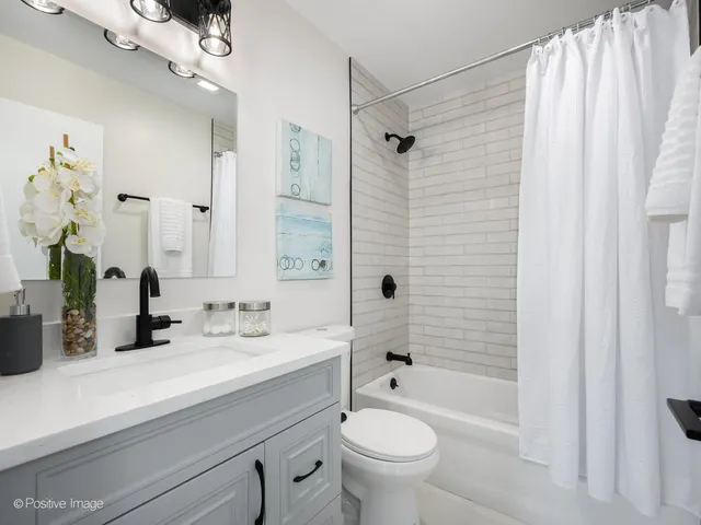 a bathroom with a sink a toilet a mirror a bathtub and shower