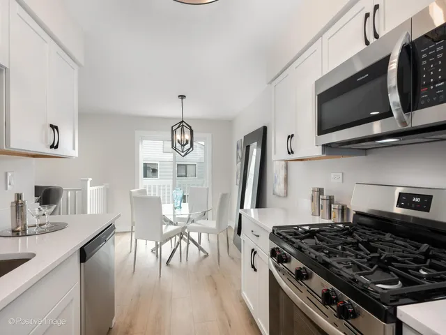 a kitchen with stainless steel appliances granite countertop a stove a sink dishwasher and microwave with wooden floor