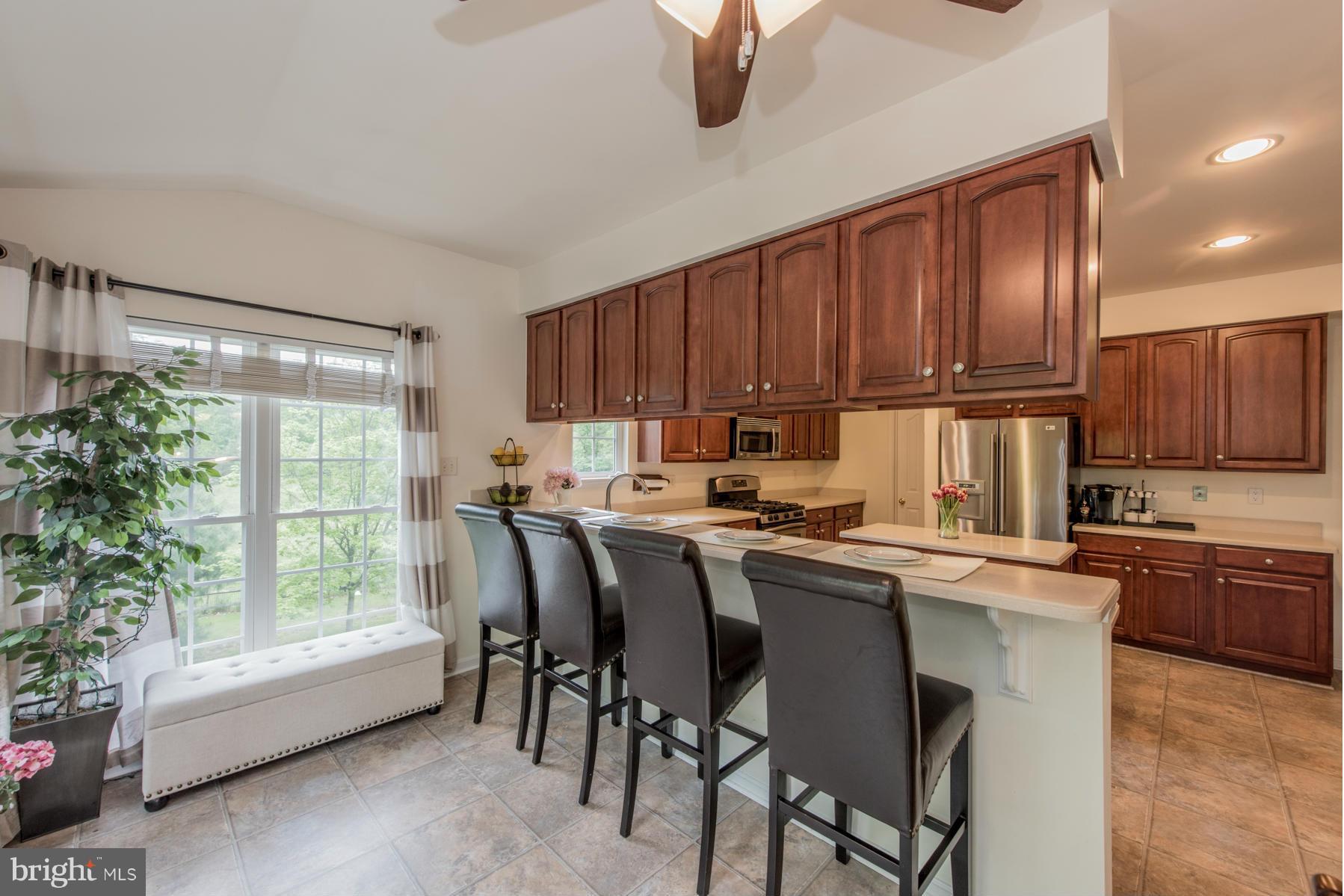 6013 Sandy Ridge Elkridge, MD 21075 - Photo 12 of 30 a kitchen with kitchen island granite countertop wooden cabinets a stove a sink with a dining table and chairs