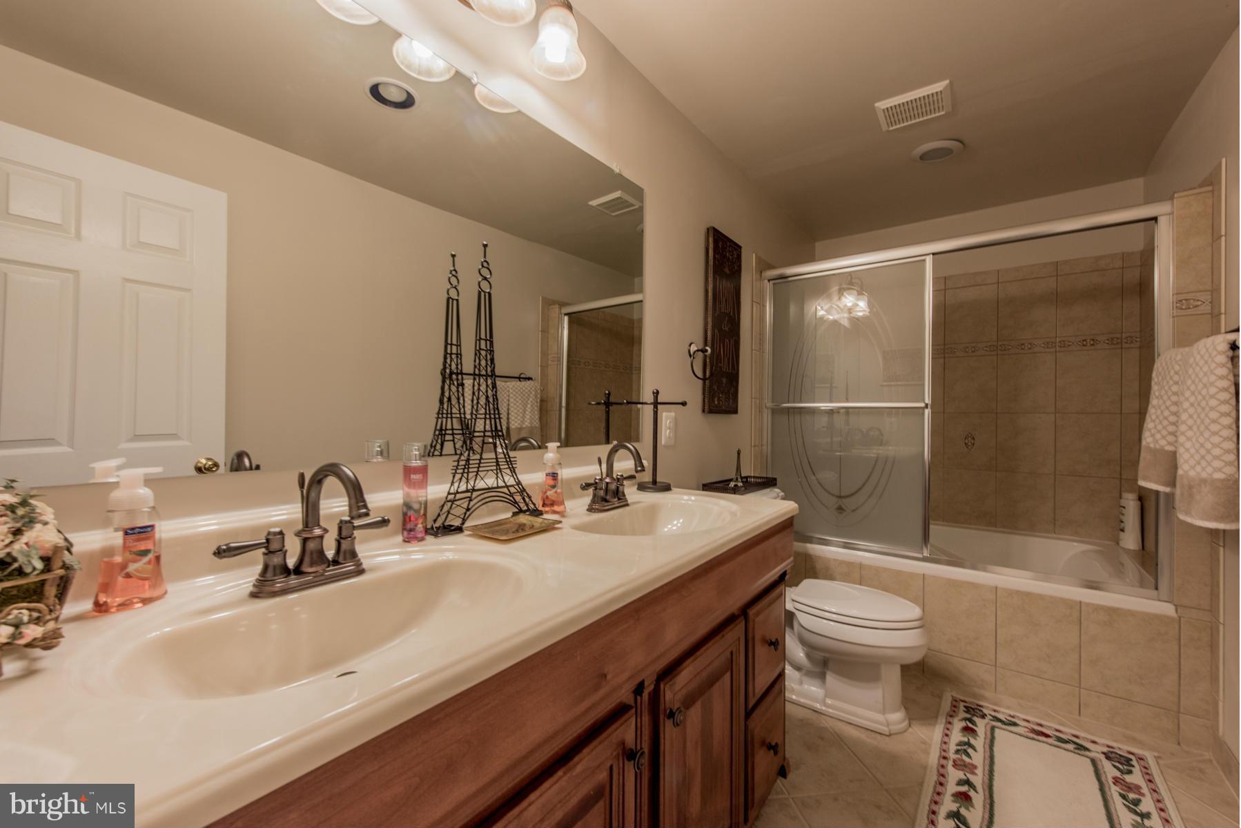 6013 Sandy Ridge Elkridge, MD 21075 - Photo 28 of 30 a bathroom with a double vanity sink toilet mirror and shower