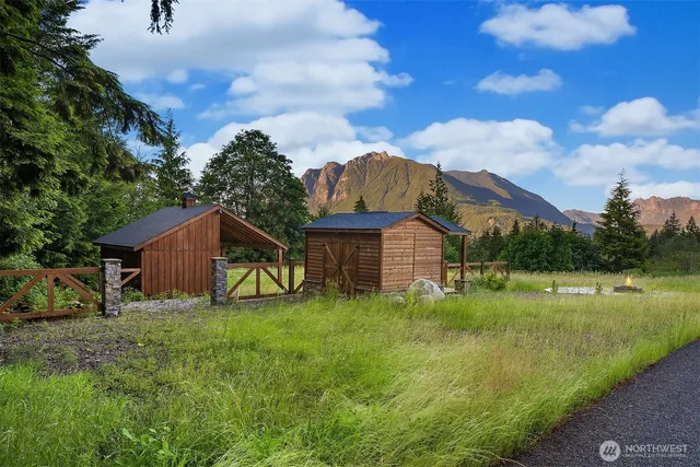 a view of a wooden house with a big yard and large trees