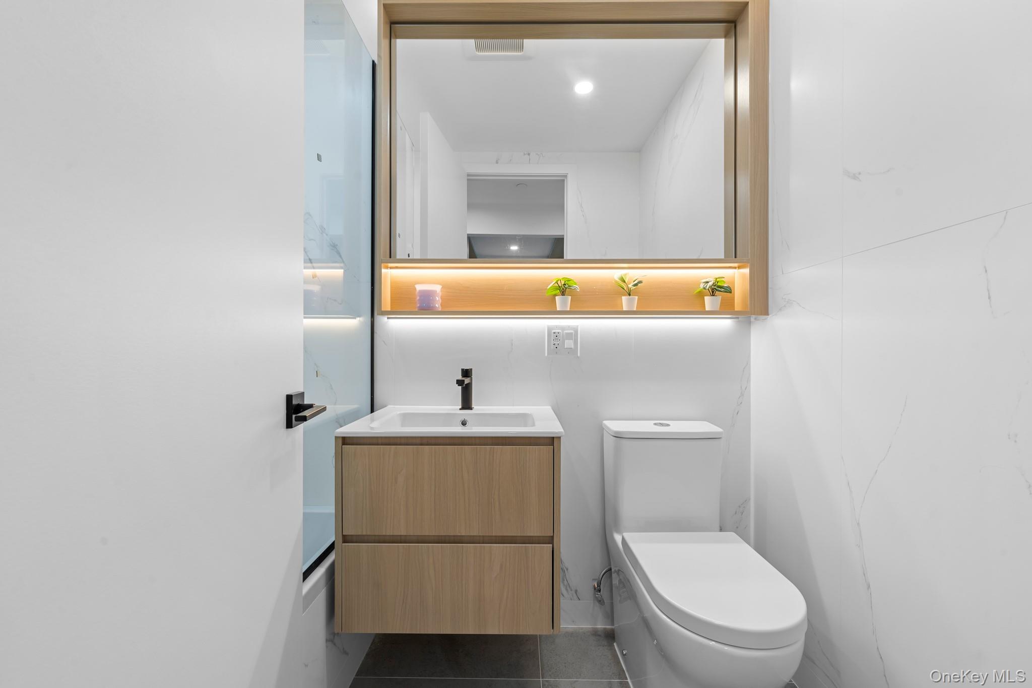 366 Harman Street, Unit 2R Brooklyn, NY 11237 - Photo 3 of 31 Half bath with vanity and dark tile patterned floors