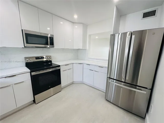 a kitchen with stainless steel appliances granite countertop a sink dishwasher a stove and a microwave oven with cabinets