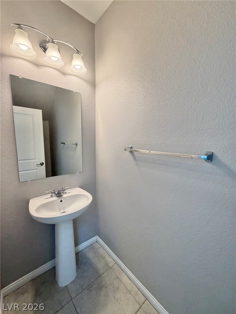 9953 Tucket Point Court Las Vegas, NV 89178 - Photo 3 of 22 A streamlined pedestal sink complements the understated wall mirror and lighting in this compact washroom.