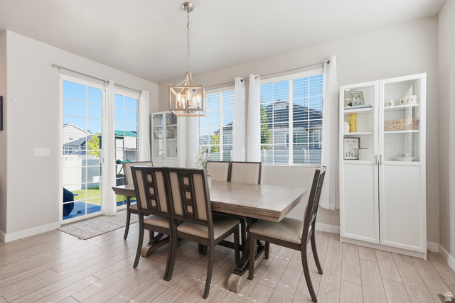 3244 West 1670th Street North Provo, UT 84601 - Photo 17 of 56 Dining area featuring wood-finish flooring, a contemporary chandelier, two large windows, and patio door access to the backyard