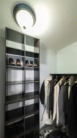 a view of walk in closet with clothes and shoes