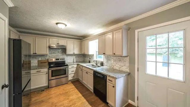 a kitchen with stainless steel appliances granite countertop a stove top oven a sink and a refrigerator