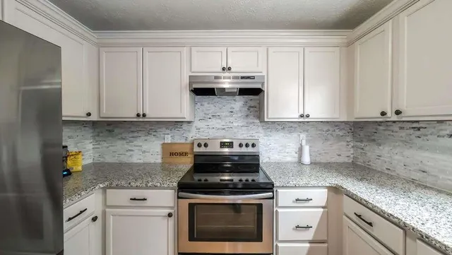 a white kitchen with granite countertop stainless steel appliances