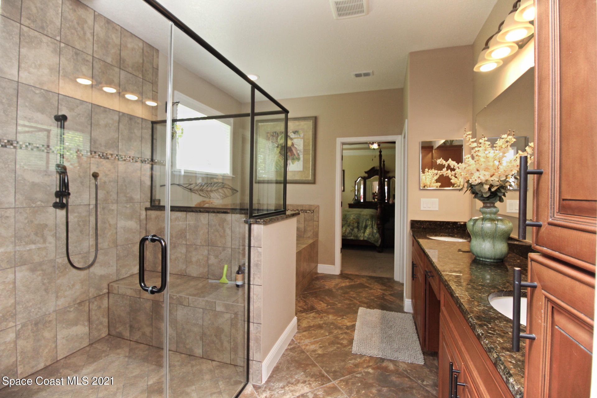 4034 Preservation Circle Melbourne, FL 32934 - Photo 16 of 25 a bathroom with a granite countertop shower a sink and a mirror