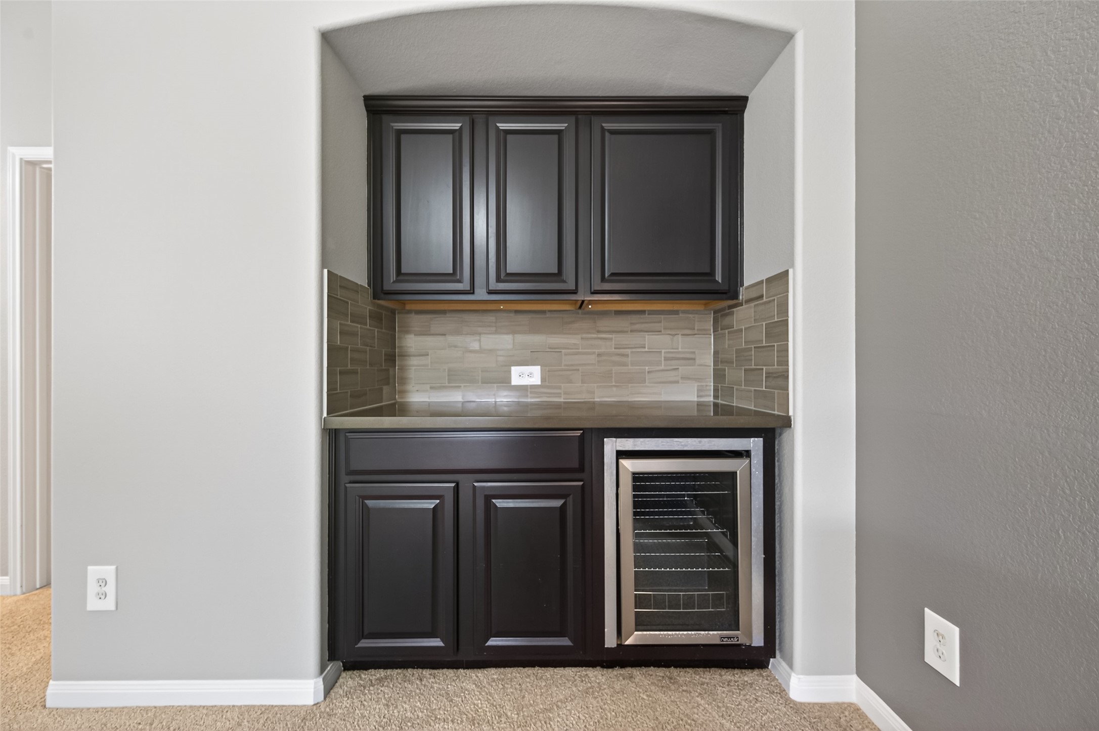 7003 Bristol Memorial Drive Spring, TX 77379 - Photo 28 of 40 Conveniently located within the upstairs game room, this built-in beverage station adds function and style to the space. Featuring rich cabinetry, a tile backsplash, ample counter space, and a built-in beverage refrigerator, it’s ideal for hosting gatherings, movie nights, or everyday convenience. Thoughtfully designed for easy entertaining, this added feature enhances the flexibility and livability of this Spring TX home.