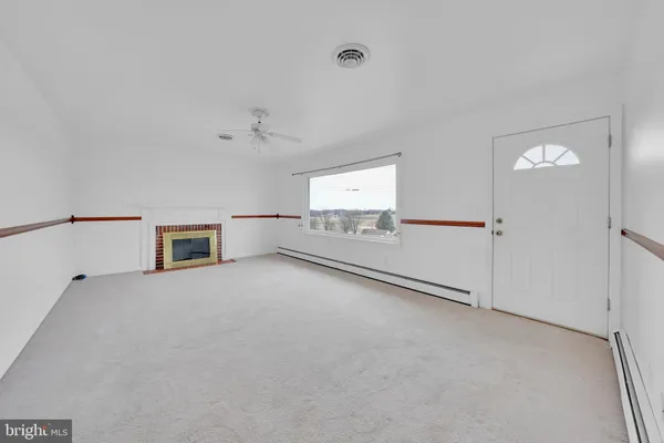 an empty room with chandelier fan and windows