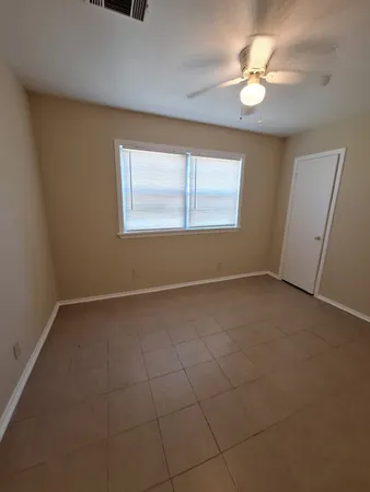 an empty room with windows and fan