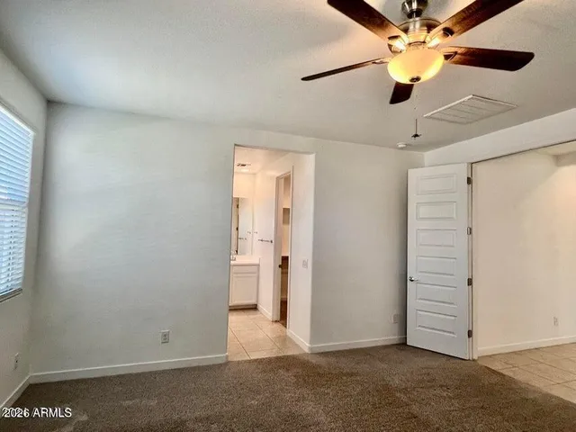 an empty room with closet and a ceiling fan