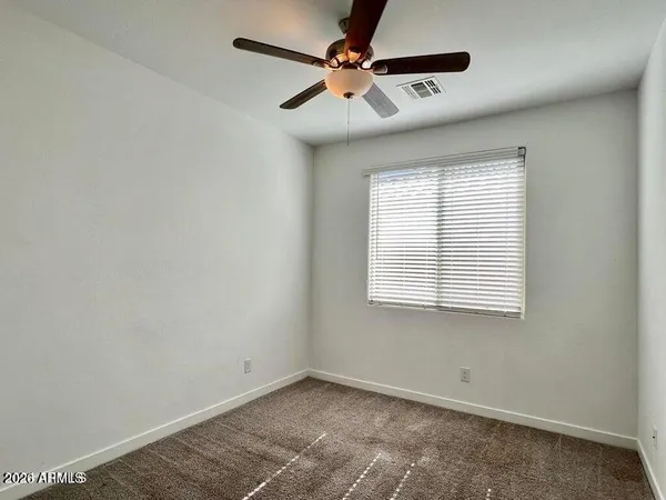 an empty room with a window and a fan