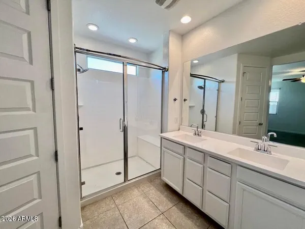 a spacious bathroom with a double vanity sink a mirror and a shower