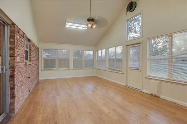 a view of an empty room with a window and wooden floor