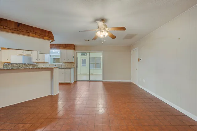 a view of an empty room with wooden floor and a ceiling fan