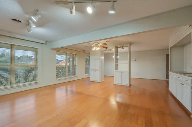 a view of an empty room with a window and wooden floor