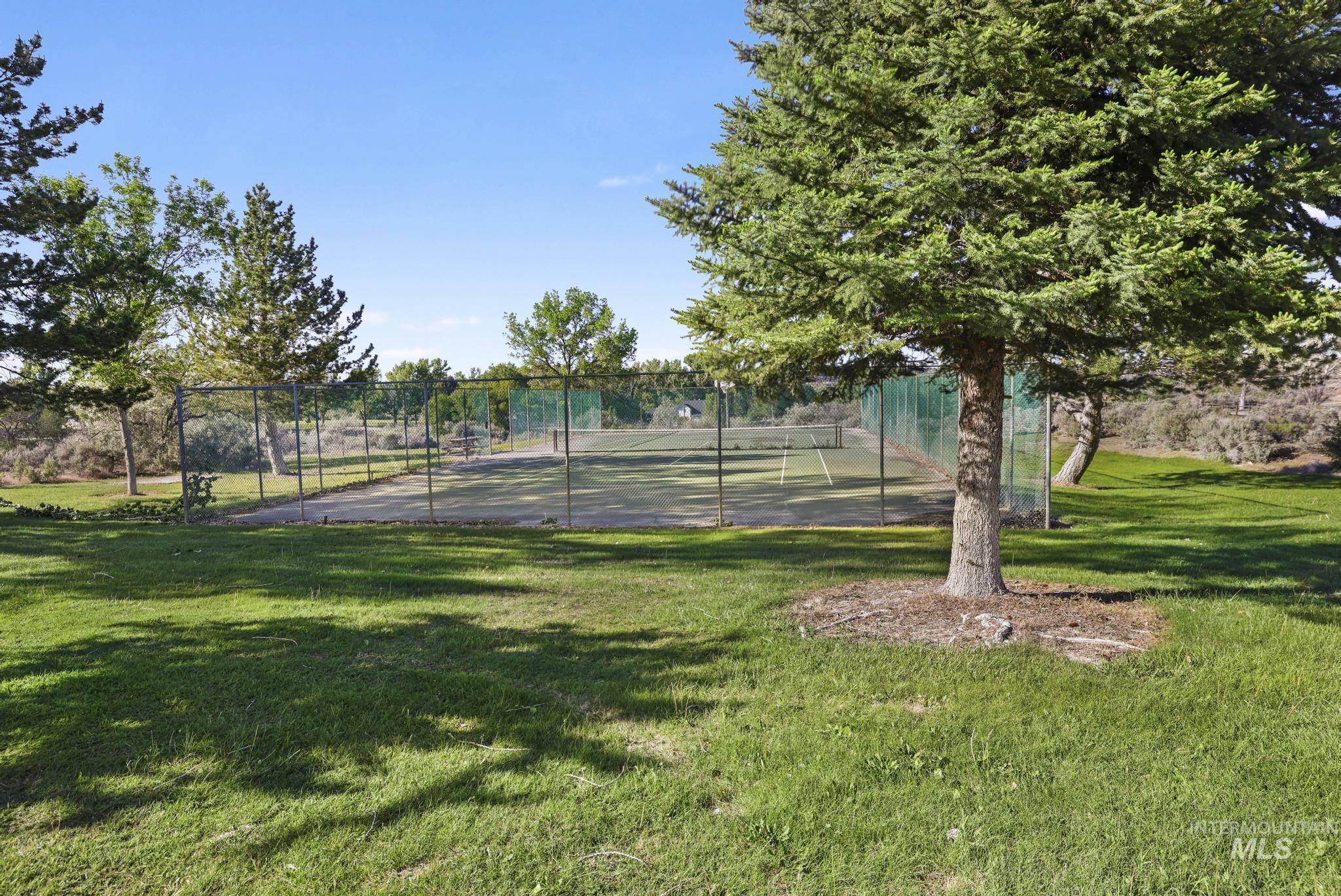 4485 Silver Creek Road Buhl, ID 83316 - Photo 40 of 49 Fenced tennis court with a green playing surface, surrounded by mature trees and manicured lawn areas