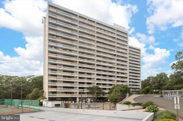 a view of an empty room with a chandelier fan and kitchen view