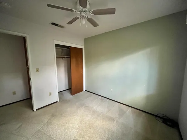 an empty room with a ceiling fan and a window