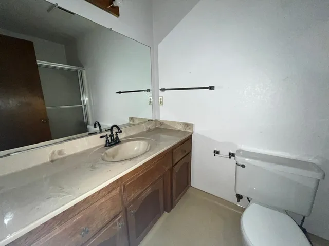 a bathroom with a granite countertop sink a mirror and a toilet