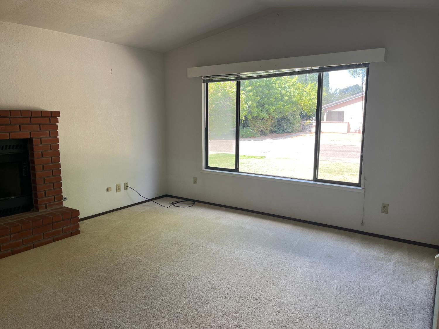 312 Roxanne Drive Patterson, CA 95363 - Photo 5 of 28 a view of an empty room with a fireplace and a window
