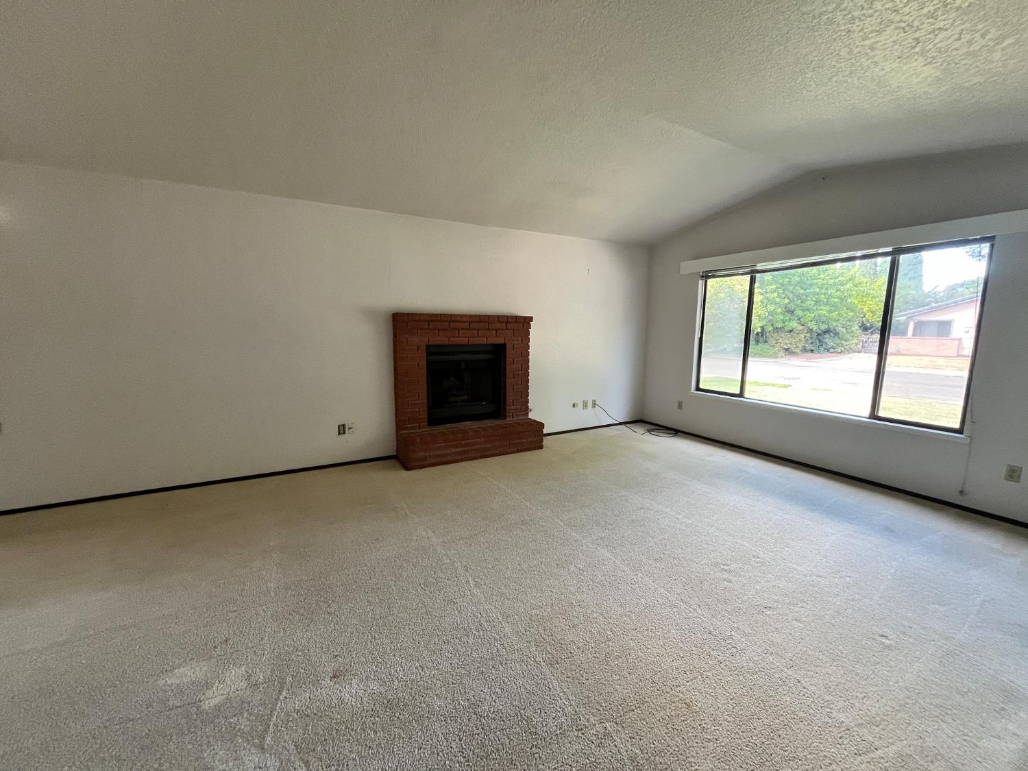 312 Roxanne Drive Patterson, CA 95363 - Photo 7 of 28 an empty room with a fireplace and windows