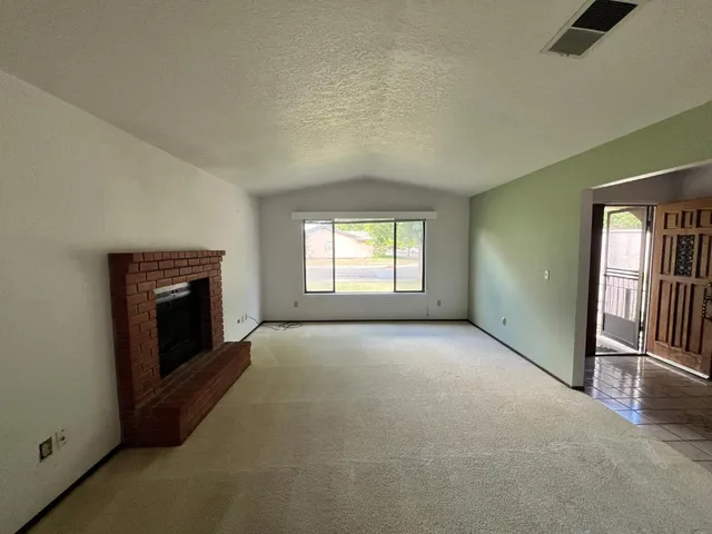 an empty room with windows and fireplace