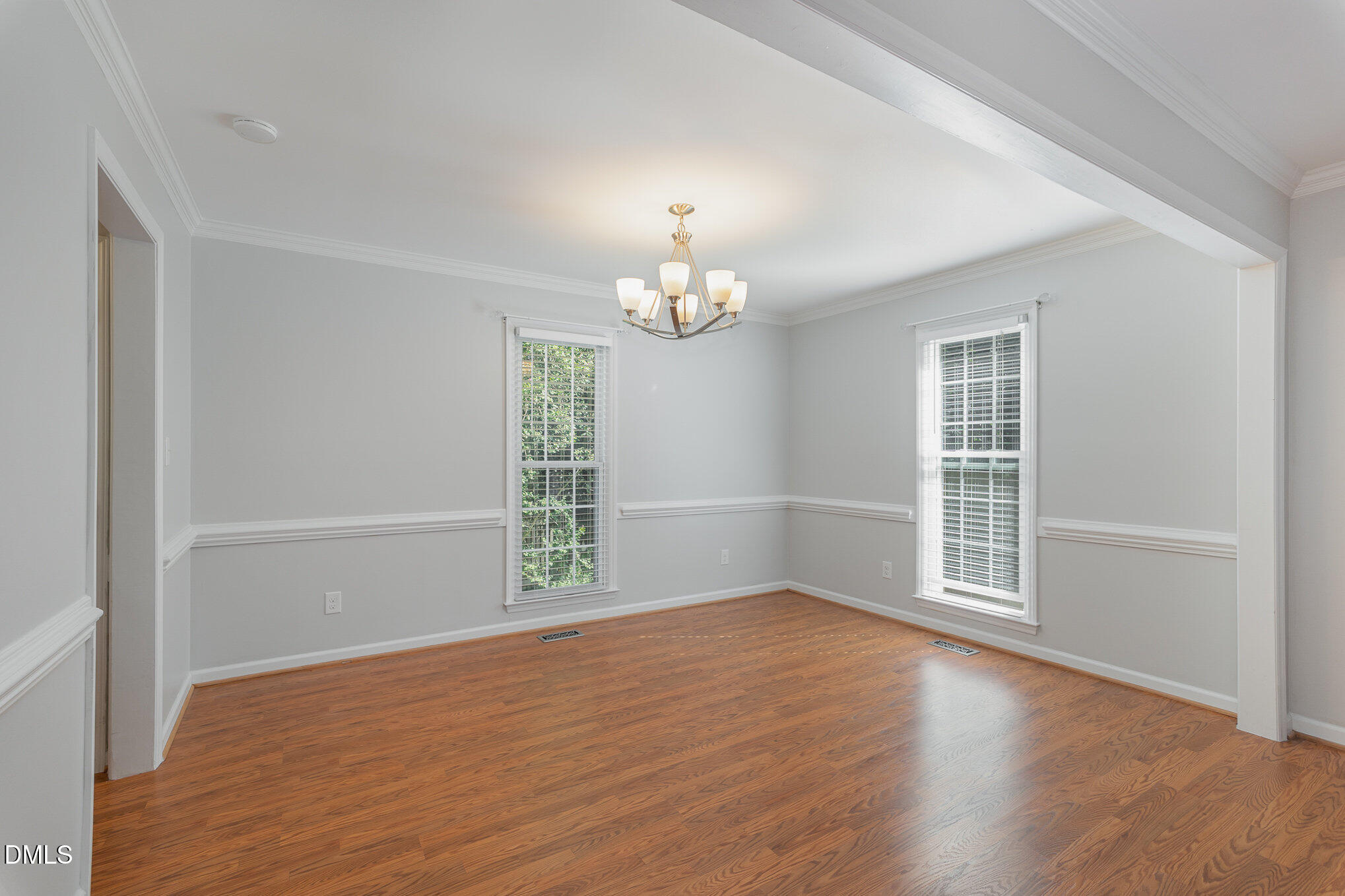 1437 Greenside Drive Raleigh, NC 27609 - Photo 12 of 27 an empty room with wooden floor chandelier and windows